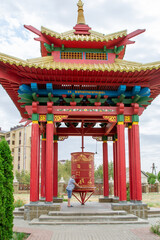 Obraz premium Ornate golden Buddhist prayer wheel. Spiritual ritual at outdoor temple pavilion
