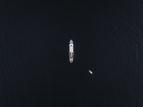 Aerial view of a yacht sailing on the dark sea, contrasting with the bright white hull of the vessel, creating a striking visual against the deep blue waters, Positano, Amalfi Coast, Campania, Italy.