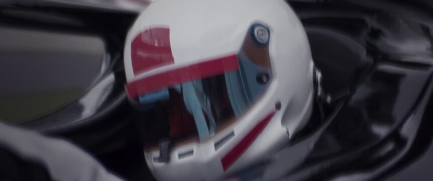 Close-up of a race car driver in a driving fast on a racing track, evening race