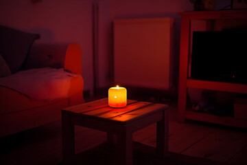 Burning candle on wooden table dimly lit room cozy atmosphere