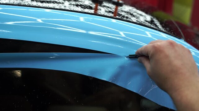 Blue PPF applied with green squeegee during detailing car to preserve finish and block damage 4k video. Applying a high-gloss blue PPF using a green squeegee ensures a bubble-free.