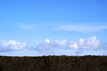 A blue sky with clouds and land on the horizon . For use as background.