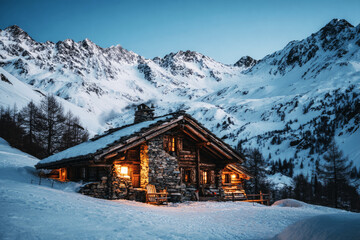A charming chalet nestled in snow-covered mountains offers warmth and comfort. Mesmerizing twilight sets a peaceful atmosphere for a perfect winter getaway