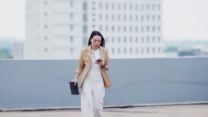 Asian office woman walking on rooftop parking lot in business attire. Symbol of ambition, change, and progress. - Powered by Adobe