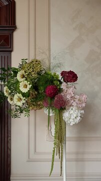 Florist adjusts a flower in a wedding flower arrangement. White, green, red tones. Hydrangea, amaranth, cosmos, ruscus