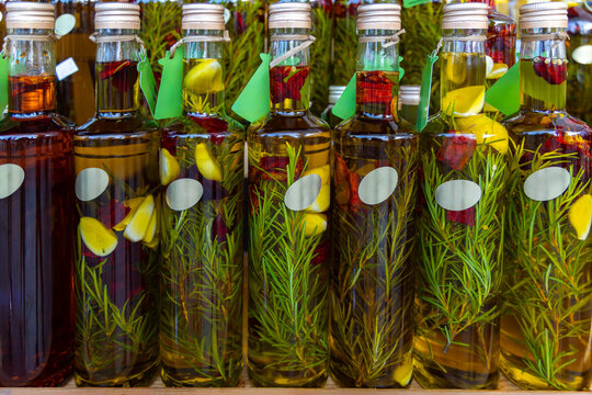 Bottles of infused olive oil with herbs and garlic. Close-up of glass bottles filled with olive oil infused with rosemary, garlic, and chili peppers, ideal for gourmet cooking themes.