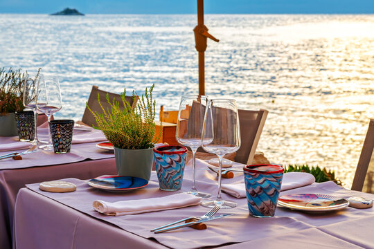 A seaside table set for dinner at sunset along the coast of the Adriatic Sea at the medieval village of Rovinj, Croatia, Istrian Peninsula.
