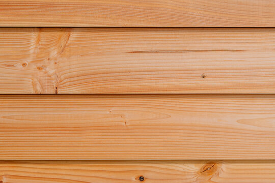 Close-up of natural horizontal wooden planks with light grain texture and warm tone. Ideal as a background, siding, or material reference in design projects.