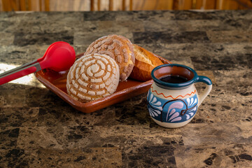 Traditional mexican hot coffee served with a variety of sweet pan dulce on a counter