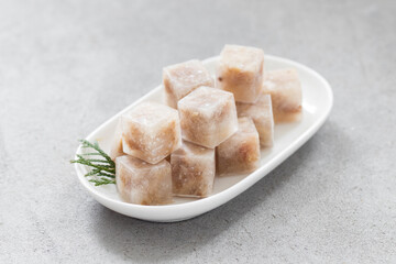 Meat jelly in the shape of a small cubes. On a white plate	