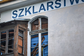 Dilapidated and weathered facade of an old building bearing the faded sign "SZKLARSIW".