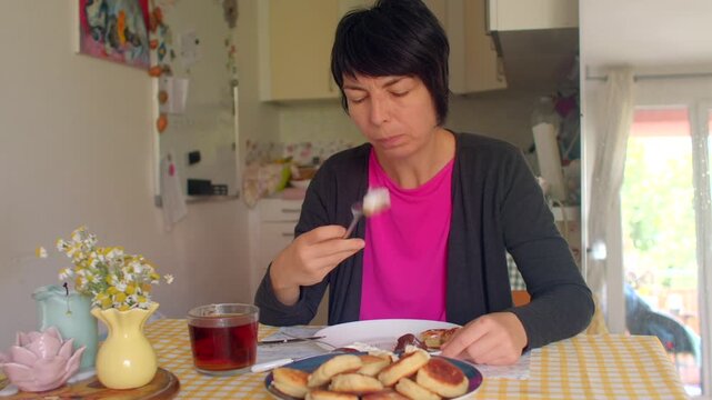 A serene scene unfolds as a woman enjoys a meal at a wellset table. She savors delicious pancakes with a fork, creating a joyful atmosphere