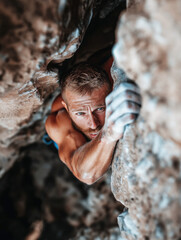 Man climbing rock wall with intense focus. Extreme sport and determination concept in mountain environment