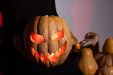 Person holding a carved pumpkin in dimly lit room, candle flickering inside, 