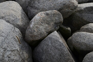 A collection of natural stones and pebbles arranged together, showcasing various textures and shapes. This close-up image highlights the earthy tones and rough surfaces
