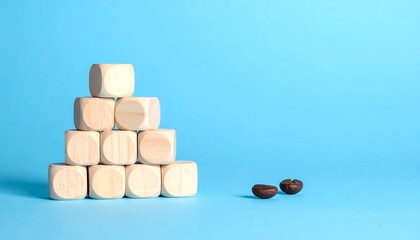 A pyramid structure of light-colored wooden cubes on a plain, vibrant blue background. Two coffee beans sit on the right