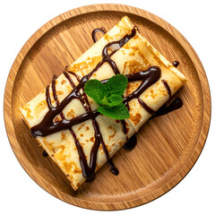 Rolled crepe dessert with chocolate drizzle and mint on wooden plate, overhead shot