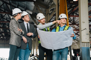 Engineers wearing safety helmets inspecting railway blueprint beside a vintage locomotive, symbolizing teamwork, innovation, and development in modern rail transportation and infrastructure projects