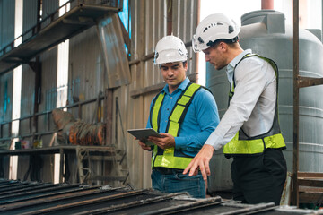 Engineers wearing safety helmets inspecting railway blueprint beside a vintage locomotive, symbolizing teamwork, innovation, and development in modern rail transportation and infrastructure projects