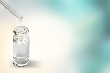 A drop falls from glass pipette in medical glass bottle