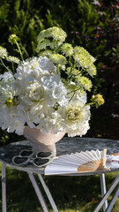 wedding street photo zone with a curved mirror, white paper umbrella, fabric, wicker basket, gypsophila, fan, white flower arrangement, hydrangea, dahlia, chrysanthemum