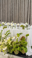 wedding decoration of the bride's table. Flower arrangement in white and green colors, vases with flowers, white tablecloth, necklace. Rose, chrysanthemum, dahlia, grapes, hydrangea, anthurium