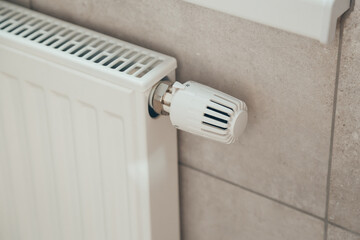 White heating radiator with thermostatic temperature regulator. Heating season. Energy saving