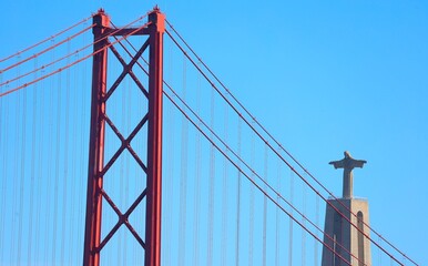 View of famous Lisbon bridge over Tagus river with Jesus Christ statue standing on the hill