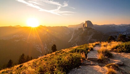 A scenic sunrise over rugged terrain reveals a rocky peak and rolling hills. The golden light illuminates a pathway and distant trees
