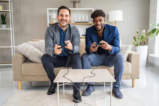 Diverse businessmen friends playing video games laughing on sofa