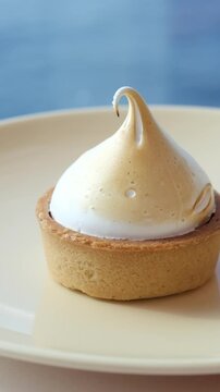 Lemon meringue tart of delicious tart dessert with meringue swirl on the top, coffee break with confectionery in a cafe. High quality 4k footage