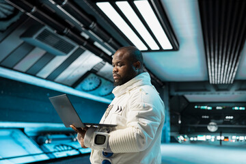 Cosmonaut in spaceship navigating orbital trajectory using laptop, doing galaxy expedition for future of mankind. Astronaut mapping unknown worlds using notebook, exploring extraterrestrial planet