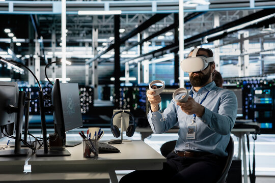 Technician using VR headset in data center to update server tech, configuring equipment using software tools. Server room employee reviewing hardware analytics using virtual reality