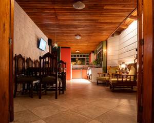 Cozy rustic interior in Baños, Ecuador. Warm lighting over wooden furniture and tiled floor, blending comfort, tradition, and Andean charm in a natural retreat.