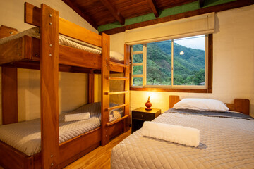 Warm rustic bedroom with wooden bunk beds and a window facing lush green mountains. Cozy lighting and natural materials create a peaceful and inviting retreat.