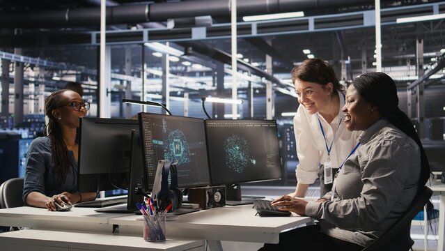 Cheerful data center technicians satisfied with results after collaborating on AI automation deployment. Happy server hub coworkers adjust machine learning configurations, working together, camera A