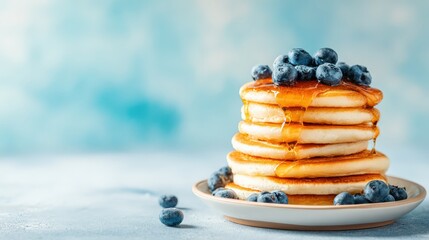 Stack of fluffy pancakes topped with blueberries and maple syrup