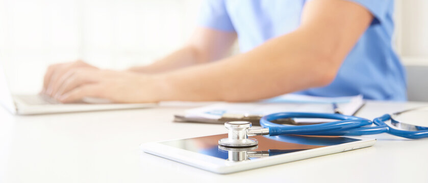 Tablet computer and stethoscope on table in clinic