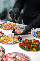 Snack bar cart with colorful and flavored candies and sweets, marshmallows, and fruit jellies for parties and events to serve in small cups.
