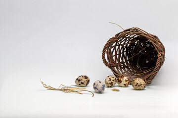 Quail eggs and a small wicker basket on a white background