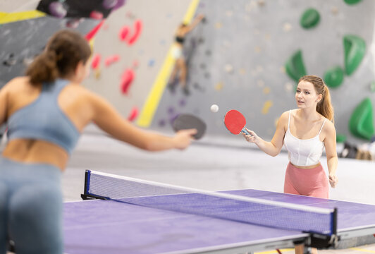 Two athletic women play table tennis with passion