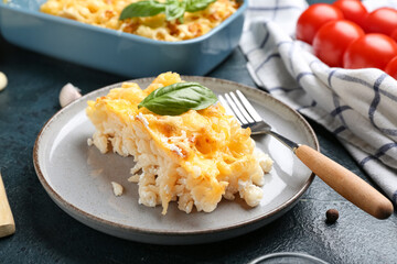 Plate with portion of baked pasta and basil leaf on blue grunge background