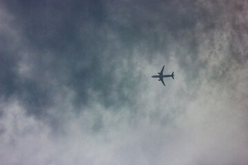 Airplane flying across a cloudy gray sky, symbolizing travel, freedom, and exploration. The contrast between the aircraft silhouette and the moody clouds creates a cinematic and atmospheric scene.