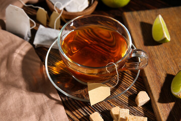 Cup of hot tea with lime slices on wooden background