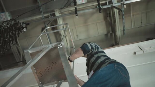 Worker climbing metal ladder in studio, adjusting lighting equipment, filming environment setup, technical production, focus on crew tasks in broadcast studio