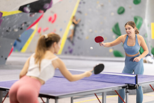 Two athletic women play table tennis with passion