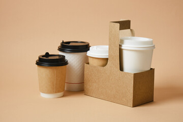 different disposable coffee cups in cardboard holder. beige background