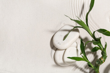 Spa stones with bamboo stem on light sand. Zen concept