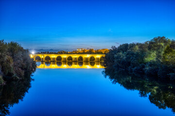 Roman bridge in Cordoba reflects amber lights at dusk