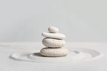 Selbstklebende Fototapeten Zen Steine Stack of spa stones on light sand against grey wall. Zen concept  © Pixel-Shot